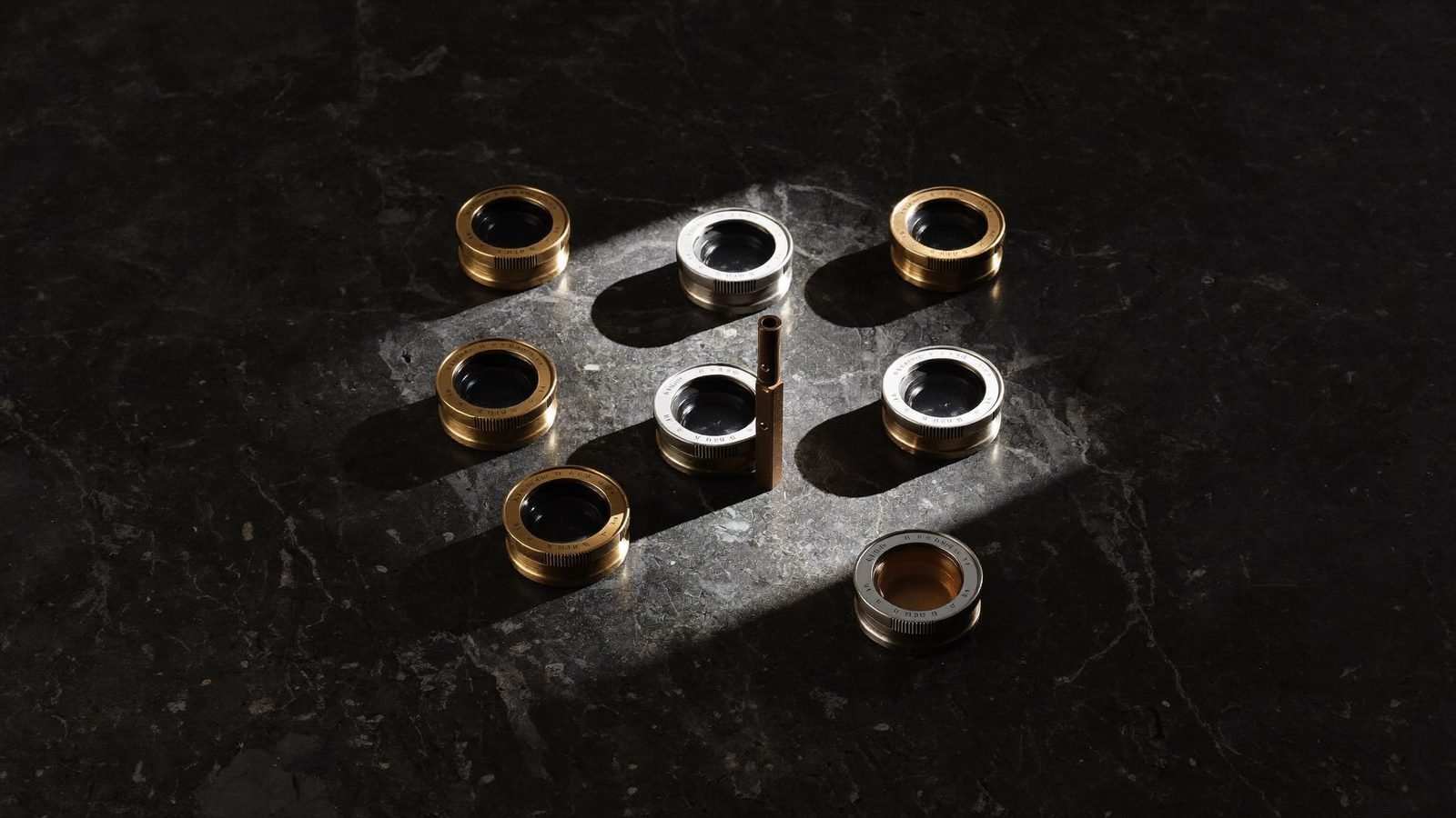 A grid of identical brass lens elements with one catching the light, representing AI UGC variant testing where only a few creatives become winners